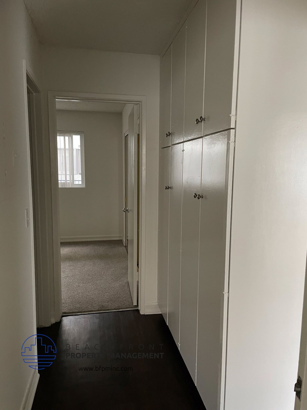a room with white cabinets and a hallway with a door to a closet